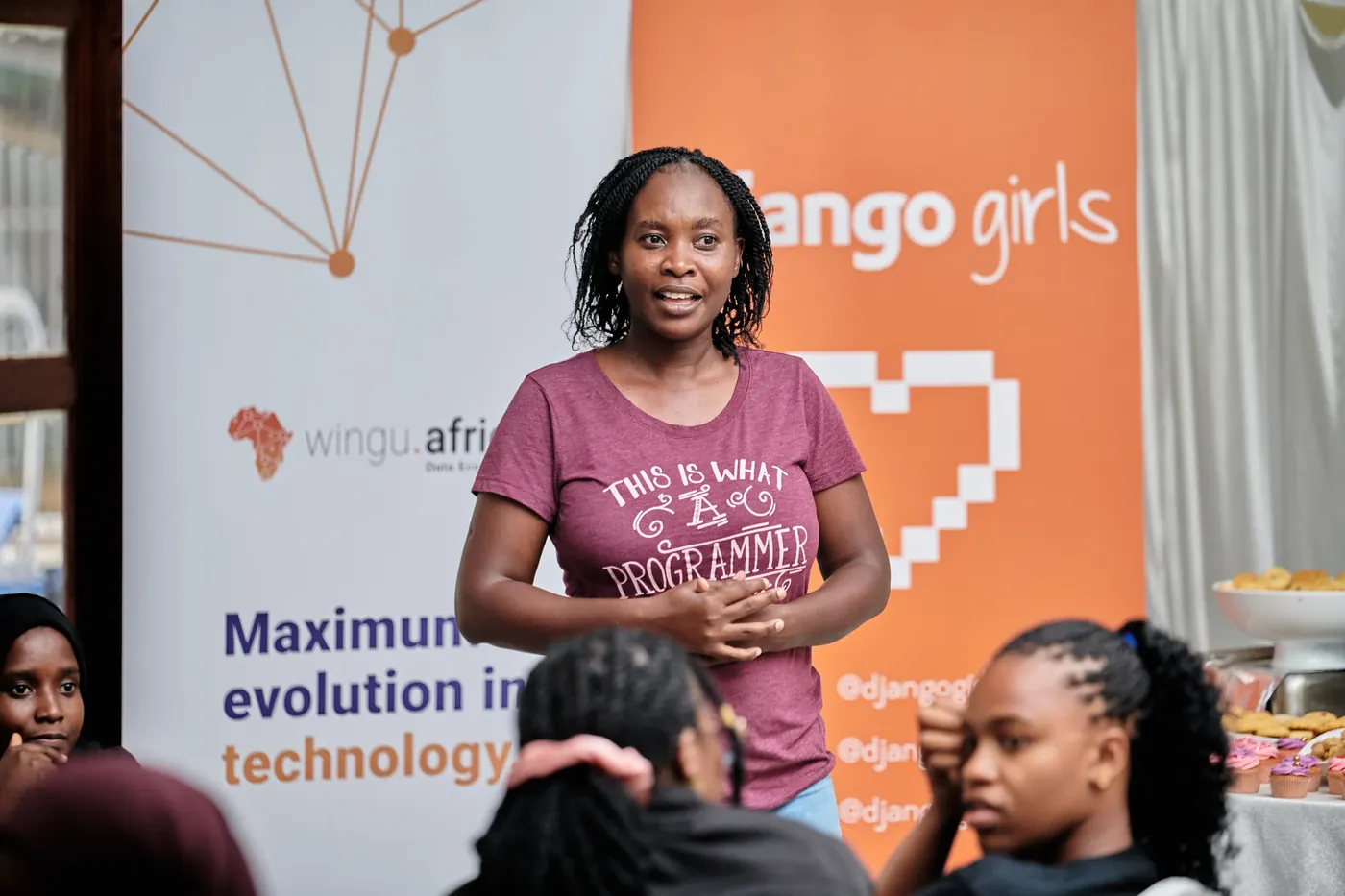 A speaker in a This Is What A Programmer Looks Like shirt addressing participants
