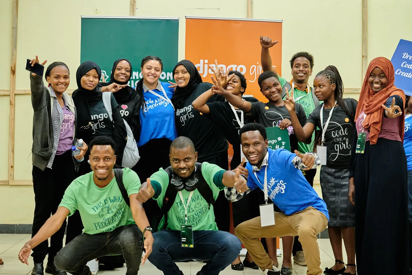 Participants and coaches cheering in front of the Django Girls banner