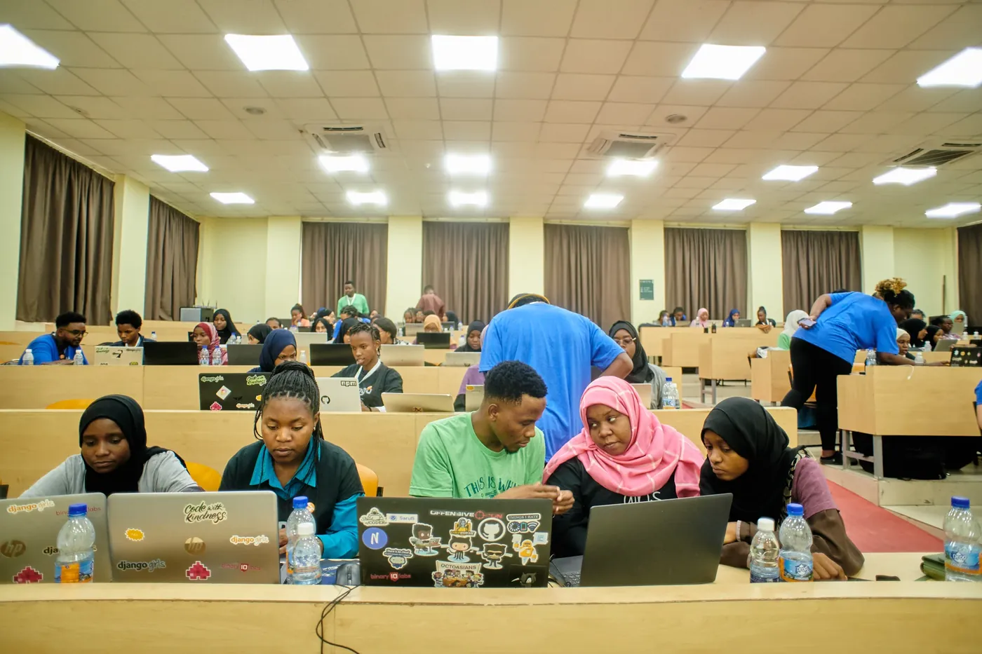 Participants coding on their laptops with a coach at a Django Girls workshop
