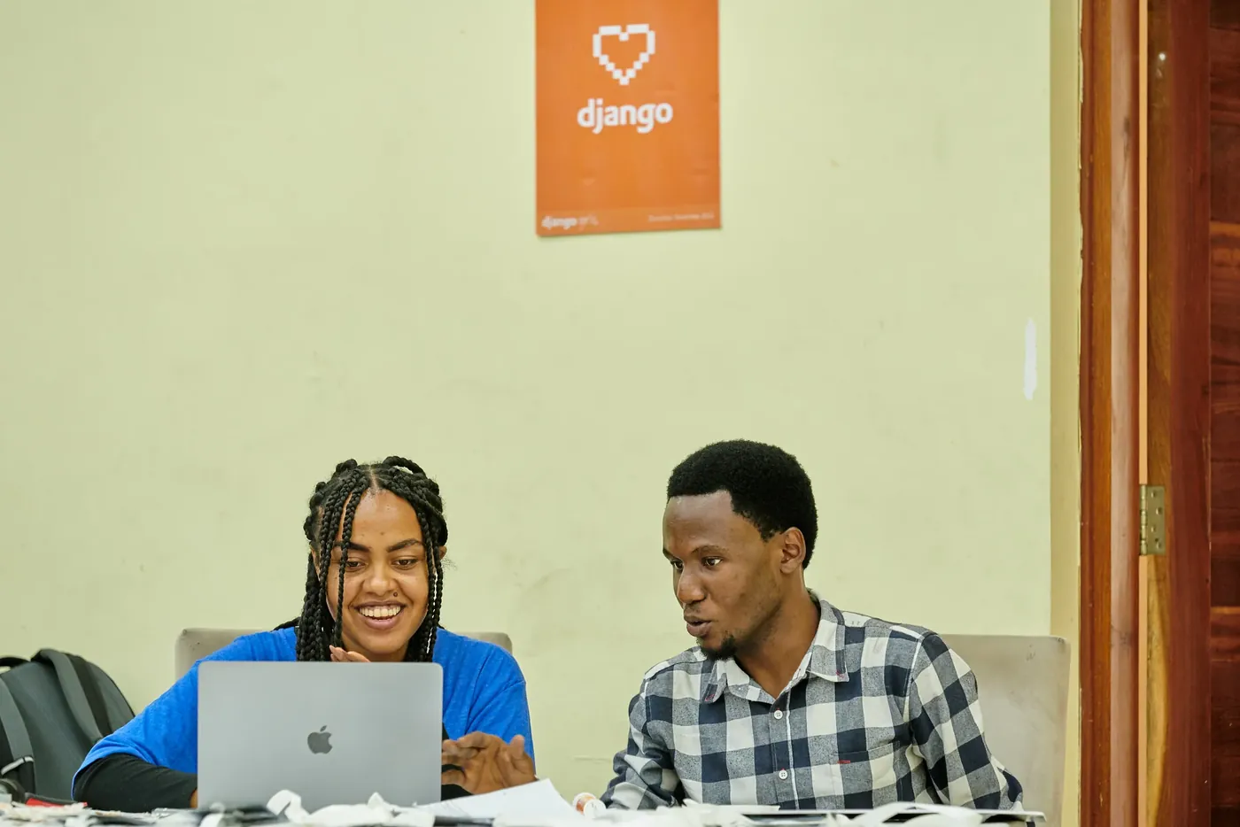 A participant and her coach smiling while working on a laptop